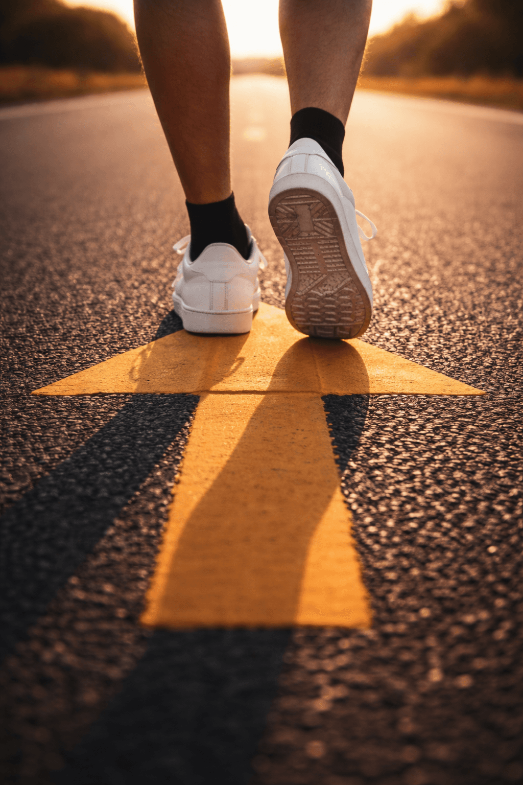 White shoes walking forward on a yellow arrow